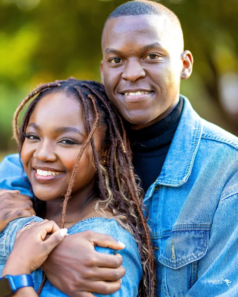 A smiling couple in denim embracing outdoors